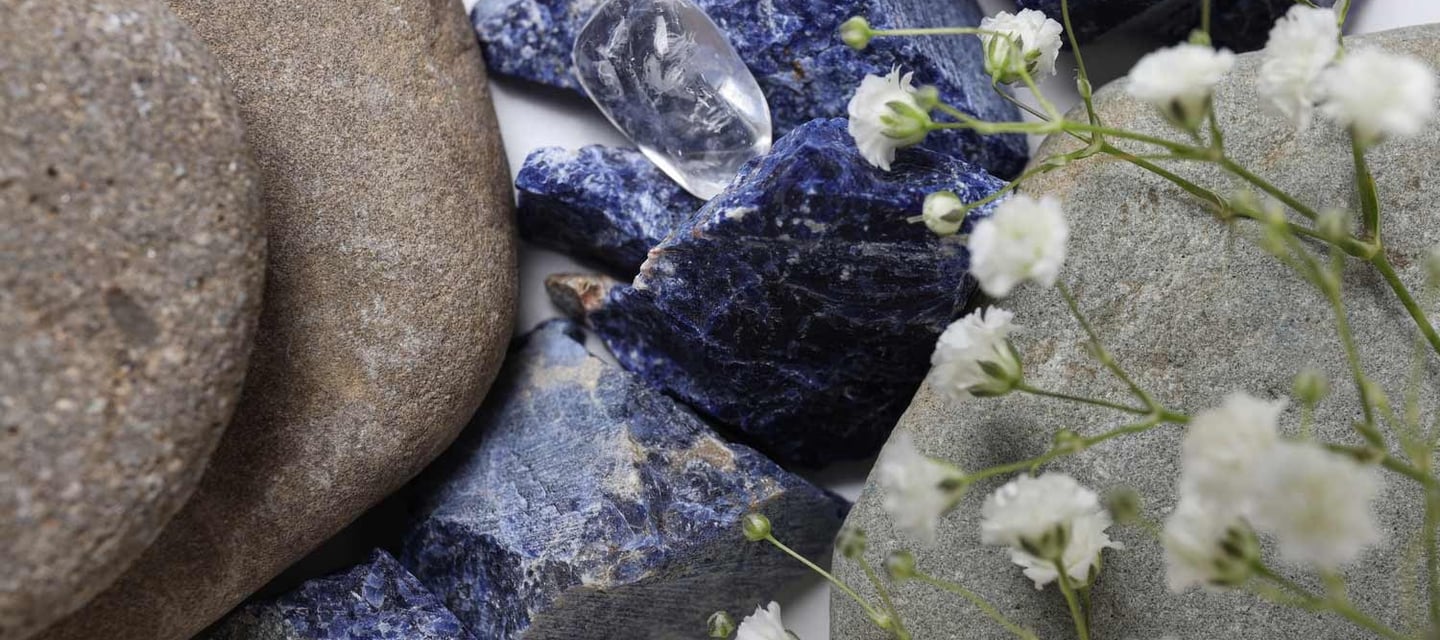 Piedras grises, azules y transparente con flores blancas encima.
