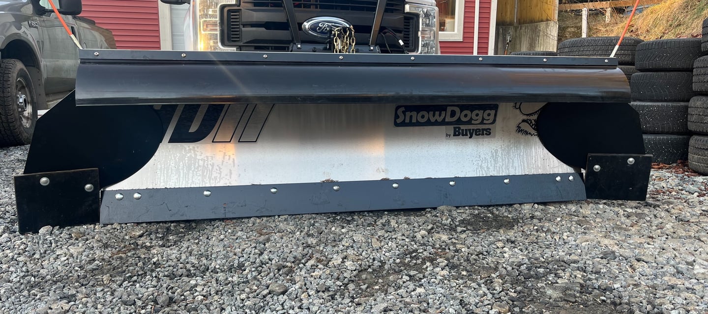 picture of the front of a white truck with a silver plow blade on it