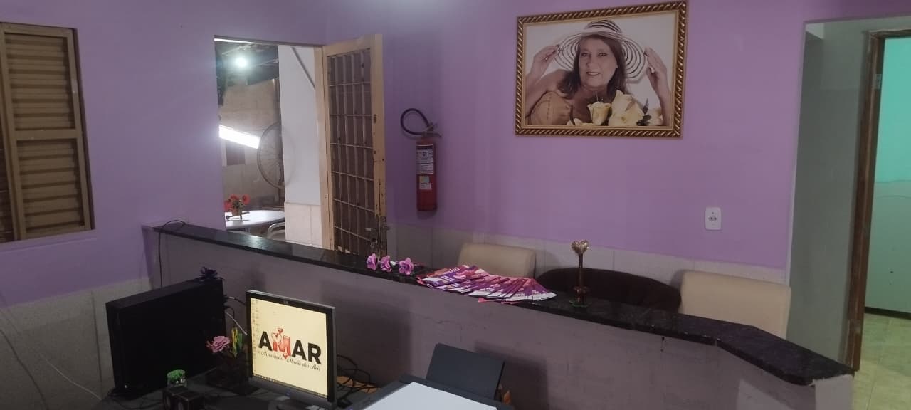 Reception area with purple walls, counter desk, computer monitor, and a framed portrait on the wall.