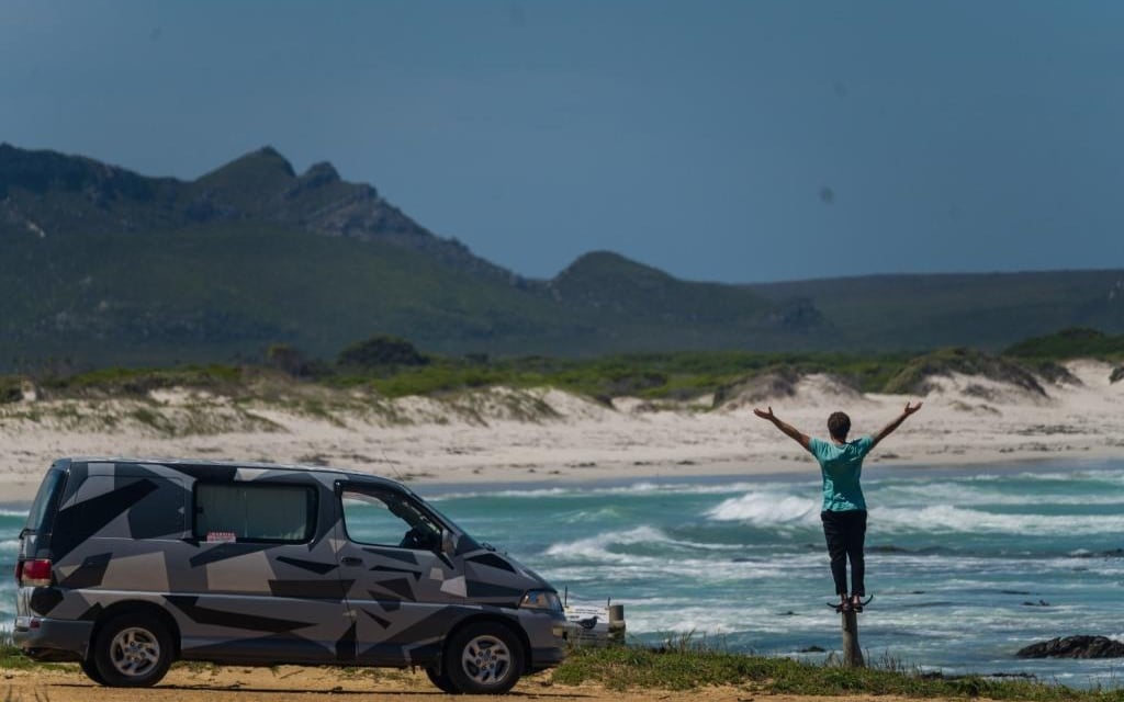 a person standing on a beach with a van