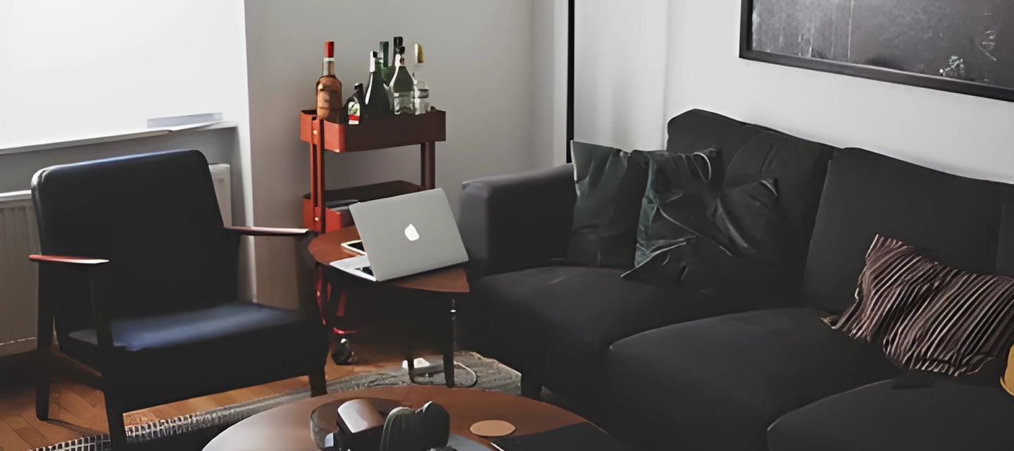 Modern living room with black leather sofa and laptop, illustrating accommodation options forstudent