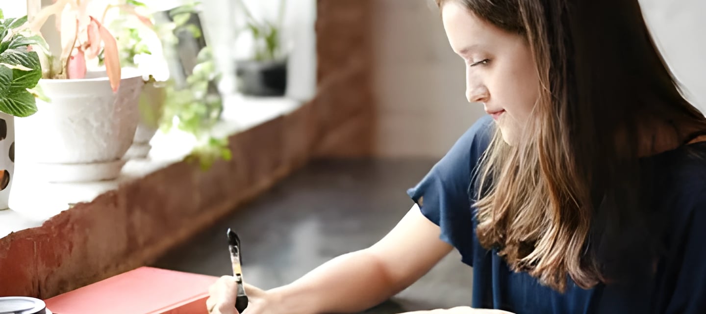 Young woman writing at a desk, symbolizing personalized guidance in crafting compelling SoPs and LOR
