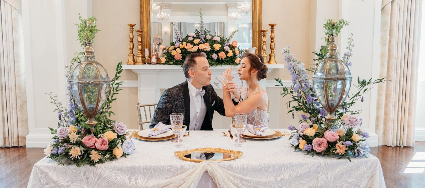 a man and woman sitting at a table with flowers