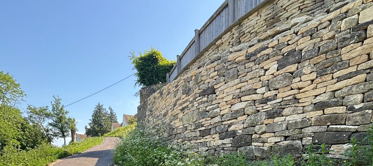 Curved retaining wall built using Cotswold stone in a rustic style