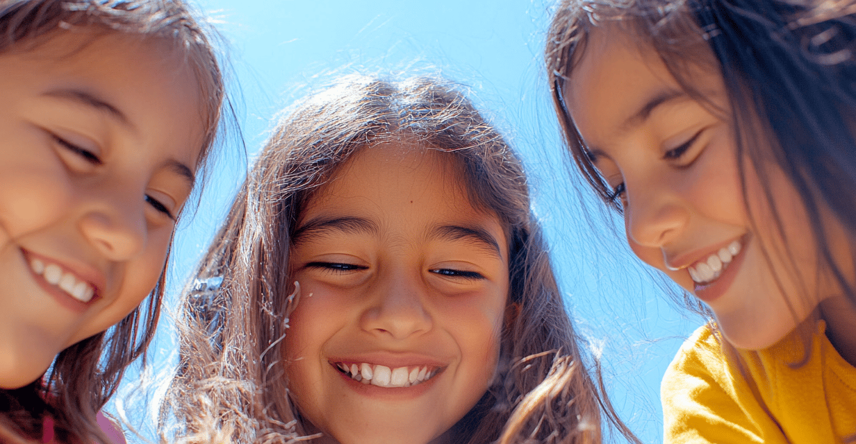 Fotografía de 3 niñas riéndose observando hacia el suelo 