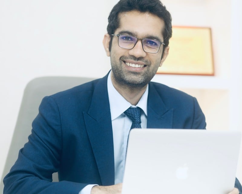 a man in a suit and tie is smiling and holding a laptop