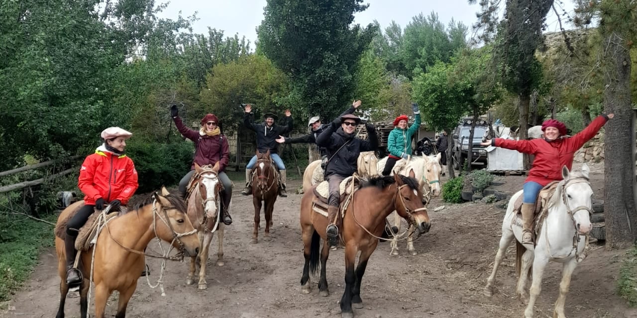 A group of people on horseback smiling and waving.