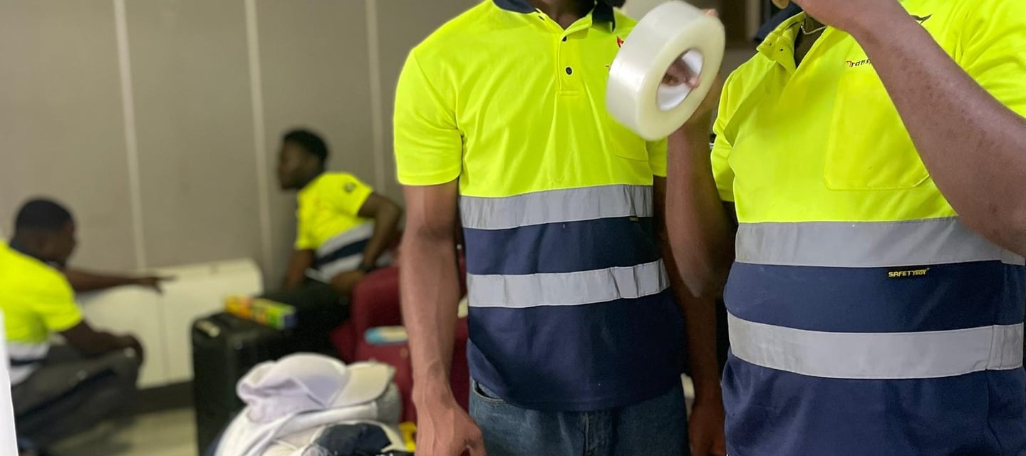 A team of four professional movers in yellow high-visibility polos with reflective stripes and "Safe
