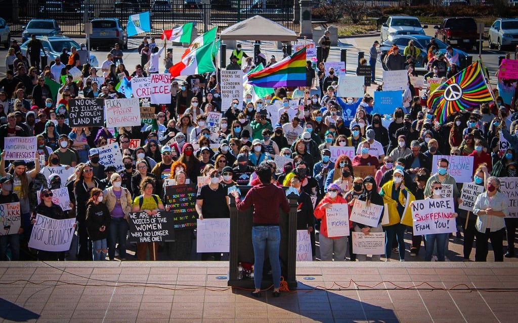 a woman standing in front of a crowd of people holding signs 