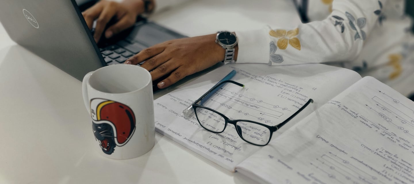 a woman sitting at a desk with a laptop and a cup of coffee