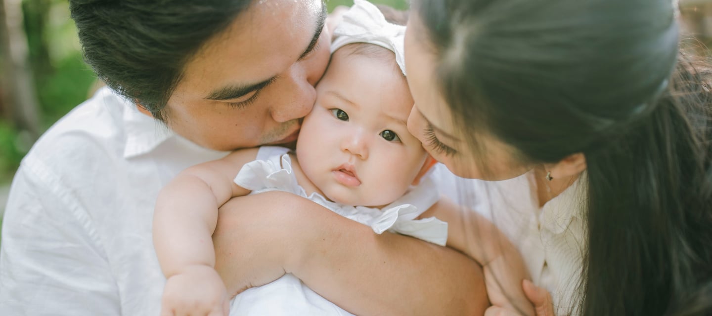 Parents kissing baby during intimate family photography session at Sofitel Nusa Dua Bali