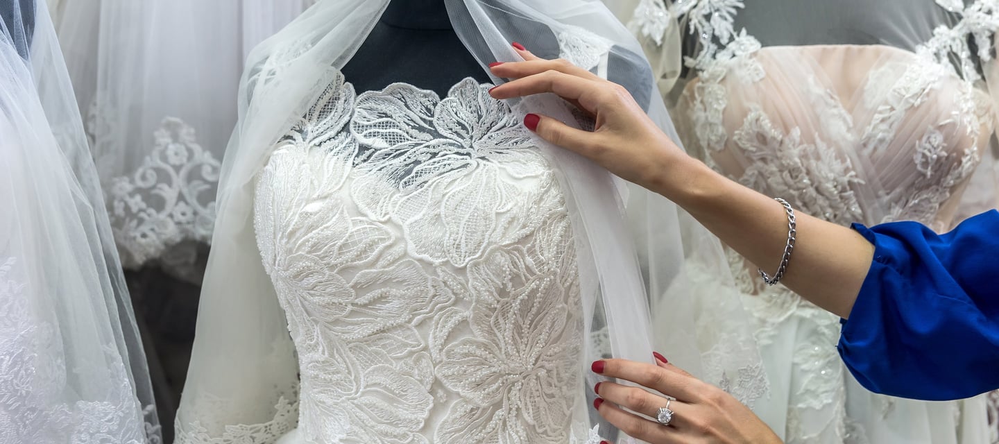 a woman is standing in front of a dress with a veil