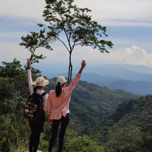 two people standing on a mountain top with their arms up