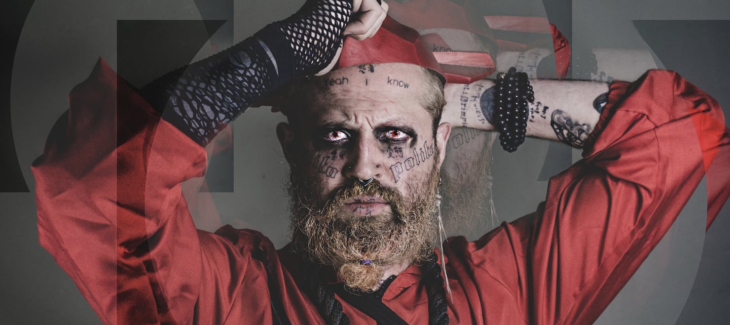 a man with a red costume, face tattoos, a beard
