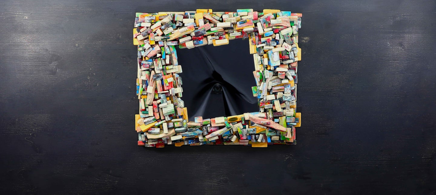 Nobler Spiegel mit kunstvollem Rahmen aus vielen kleinen, bunt gefärbten Holzscheiten.