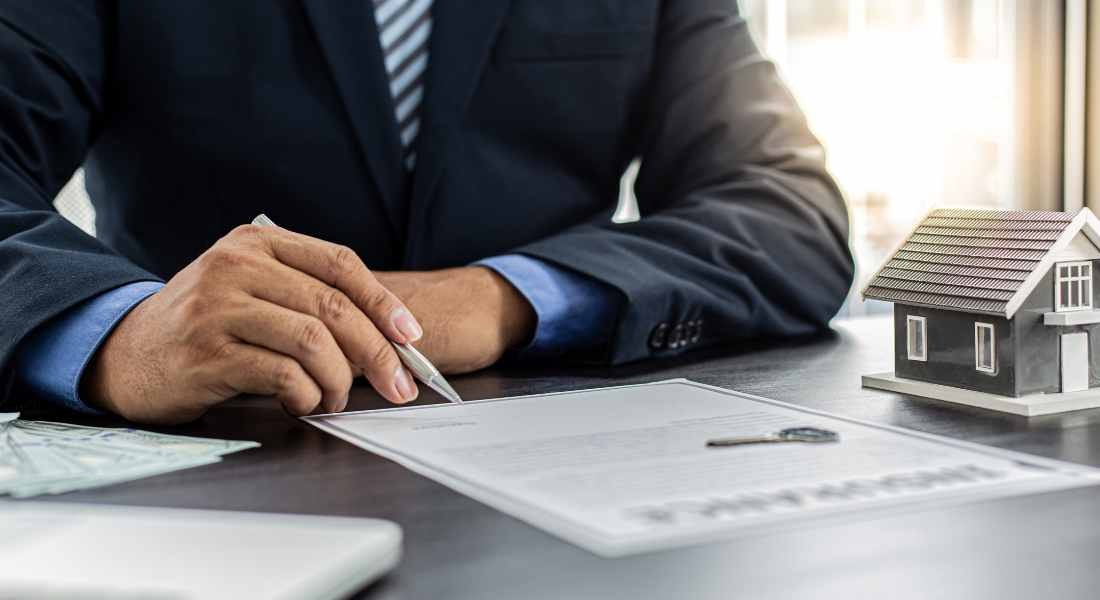 a man in a suit and tie is sitting at a desk with a pen and