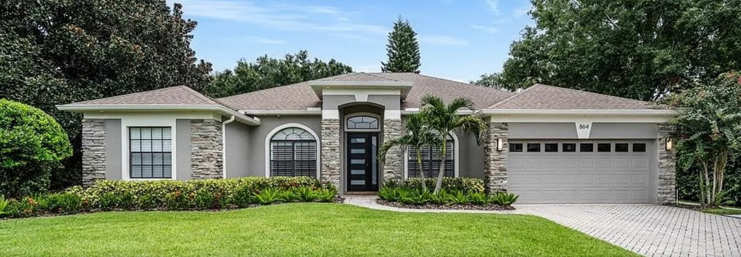 Exterior of a single-story home with a stone-accent facade, front entry door, and attached garage.