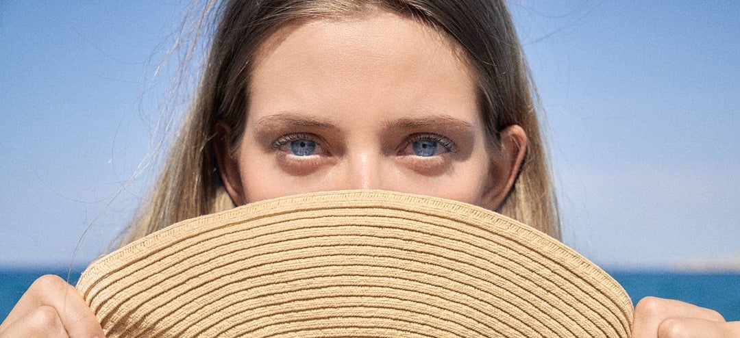 Close-up of blue eyes of a young girl partially hidden behind a hat