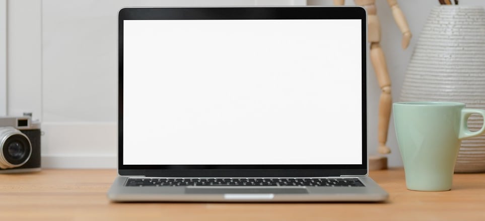 Laptop on desk with camera and mug