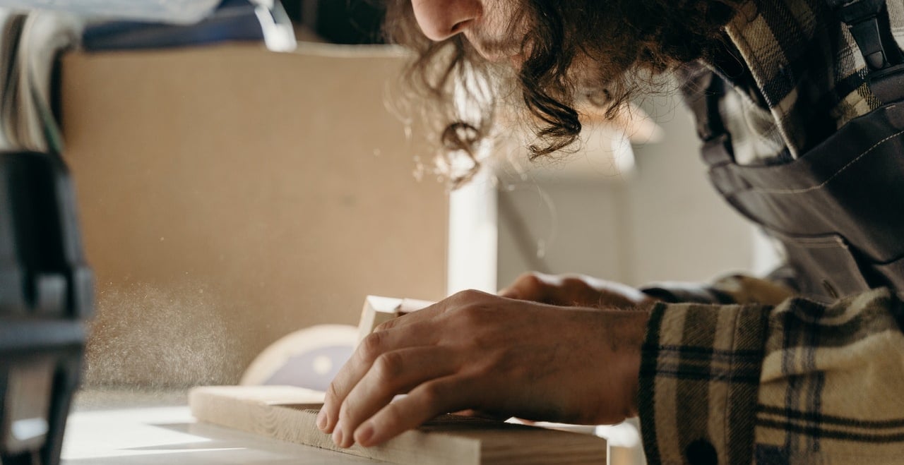 Kobieta obrabia papierem ściernym element z drtewna