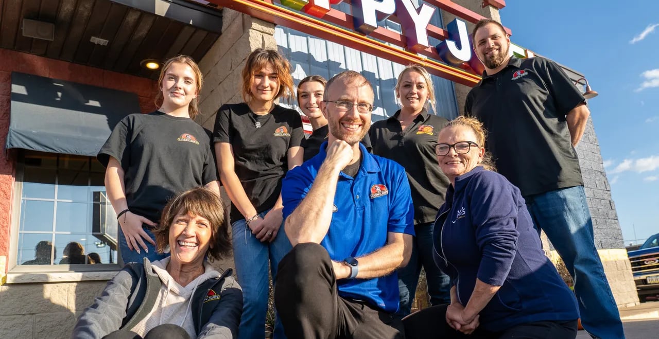 a group of people standing in front of a happy j j's restaurant