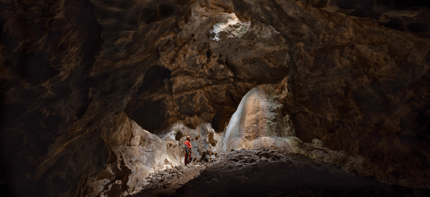 Persona explorando el interior de la Cueva la Tinaja, en un ambiente oscuro y misterioso