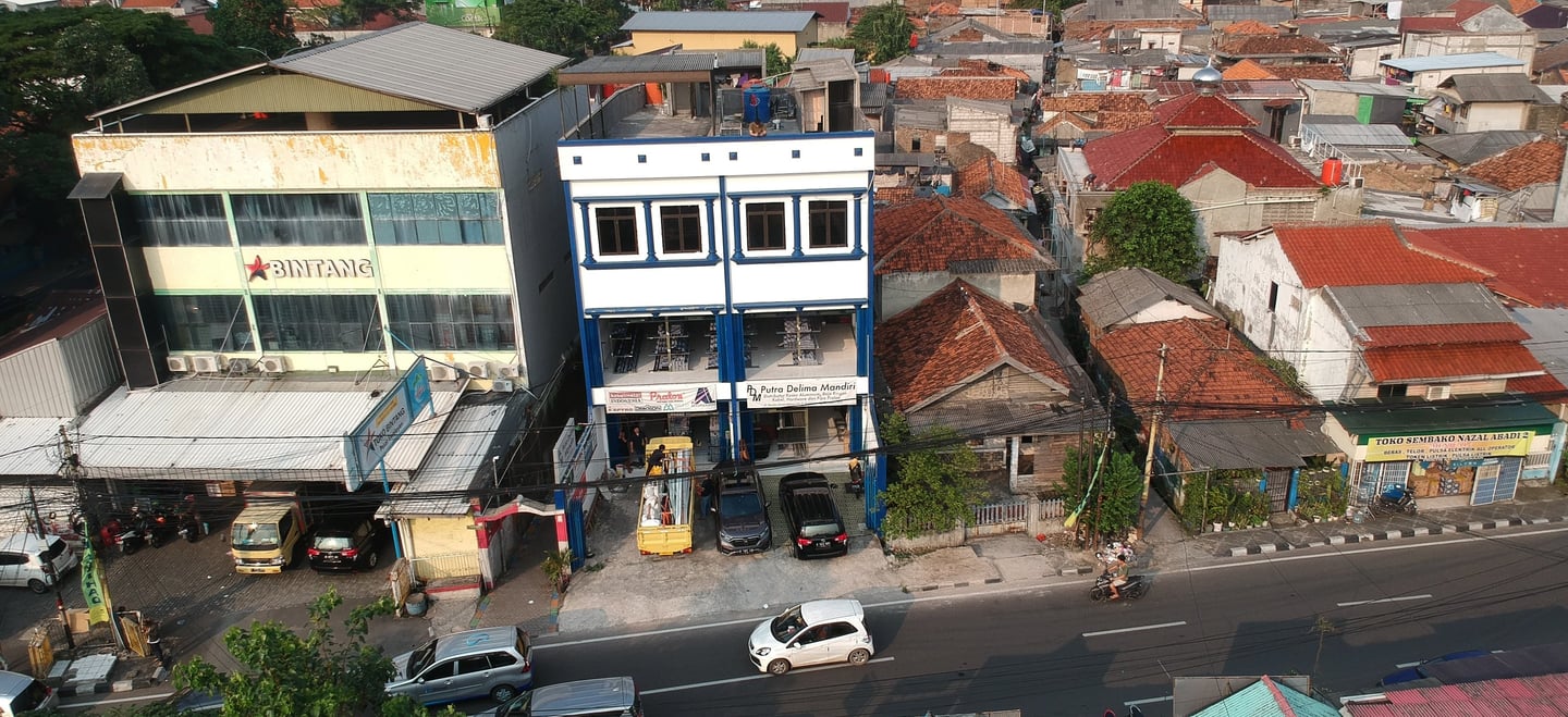 a city street scene with a car parked in front of a building gedung kantor putra delima mandiri