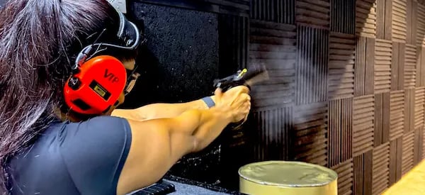 mais alhajri shooting a handgun at an indoor shooting range wearing protective gear