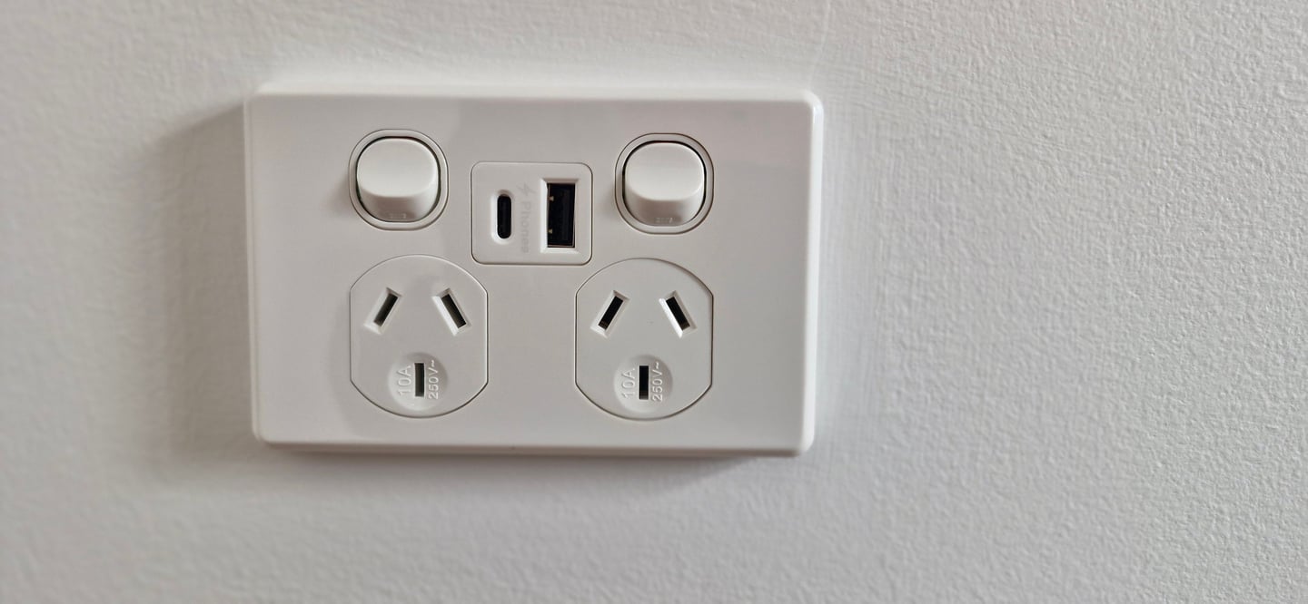White double power point with USB-A and USB-C ports on a modern white wall.