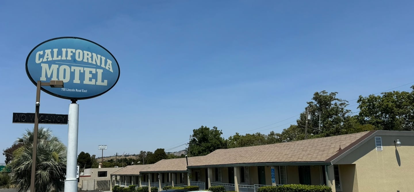 a motel sign that says california motel with the motel in the background and a blue sky