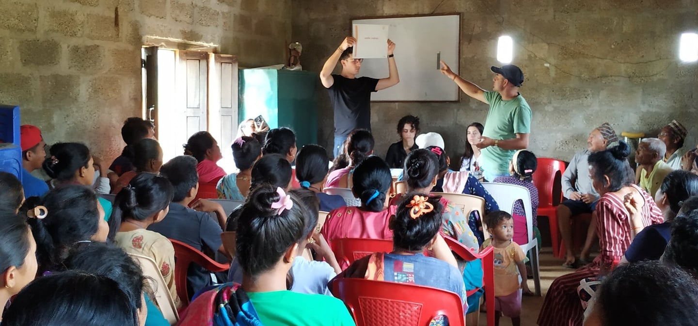 Roger Solà leading a workshop for a group of local villagers in a rural stone building.