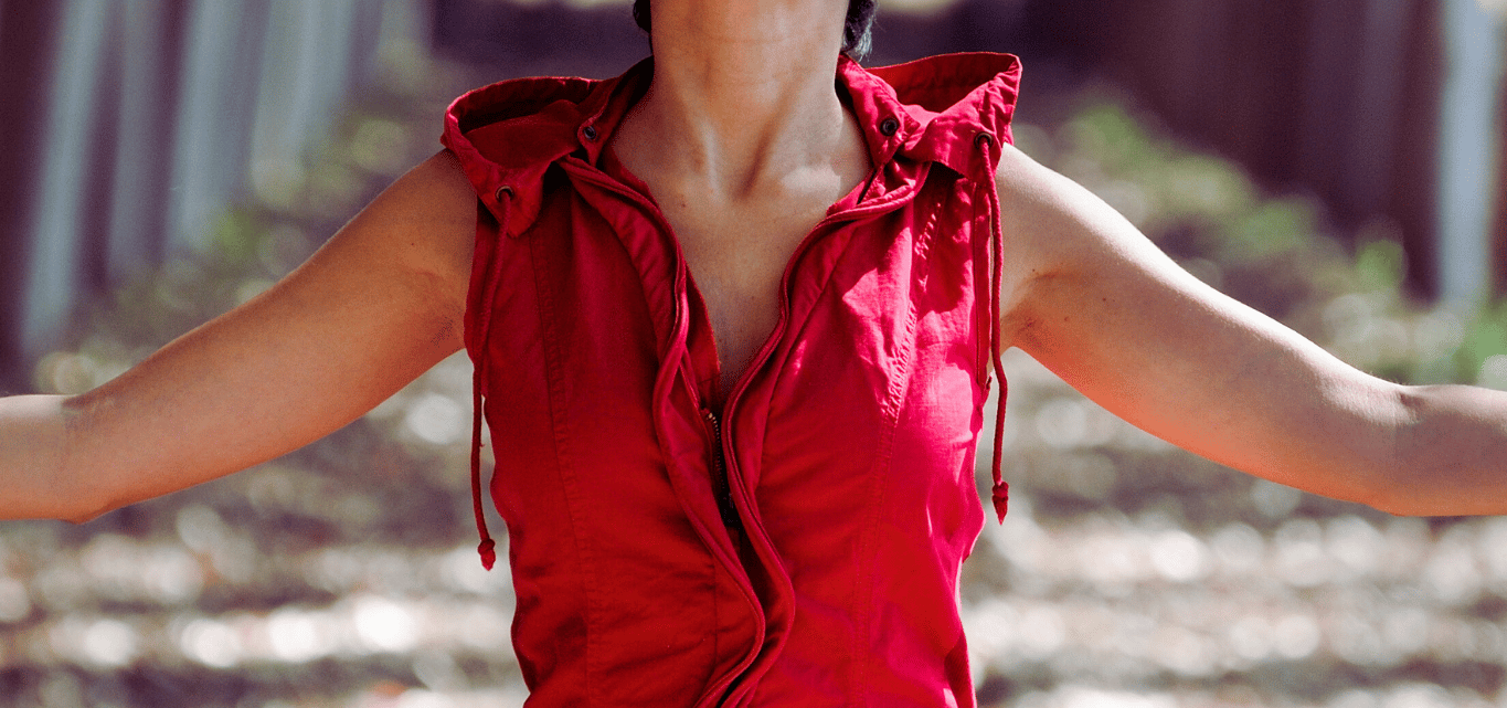 Empowered woman in red dress in the forest, symbolizing financial and spiritual freedom 