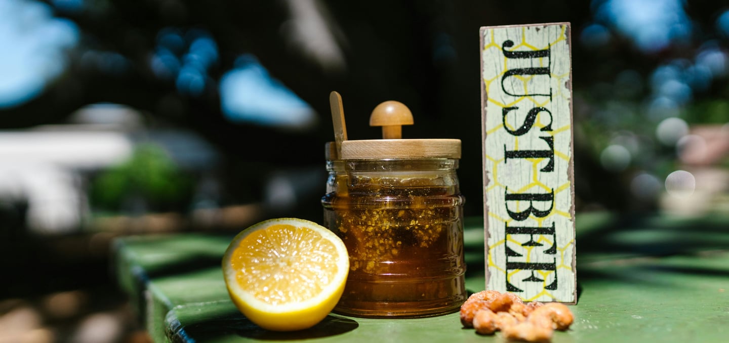 Honey jar on table with lemon and nuts