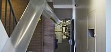 a long metal pipe in a hallway with a sink and a sink