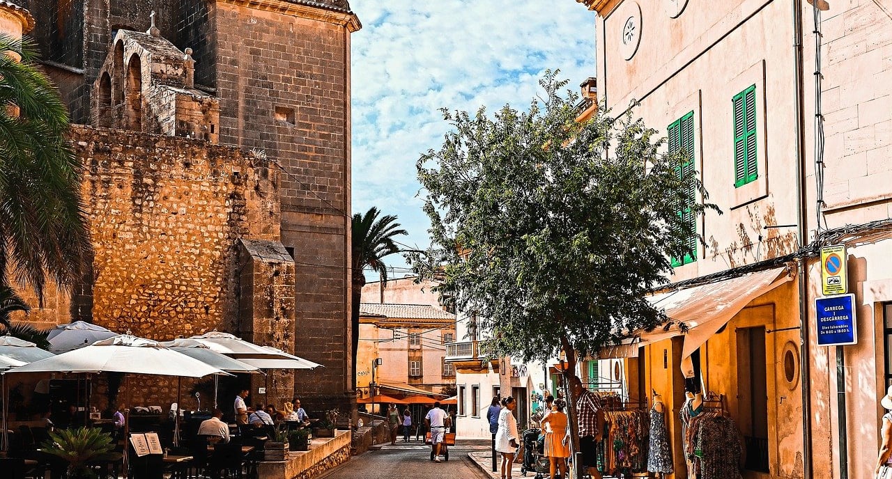 Town in Mallorca with people walking and sitting near an old building