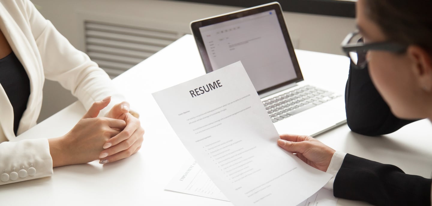 a woman in a white suit and glasses sitting at a desk