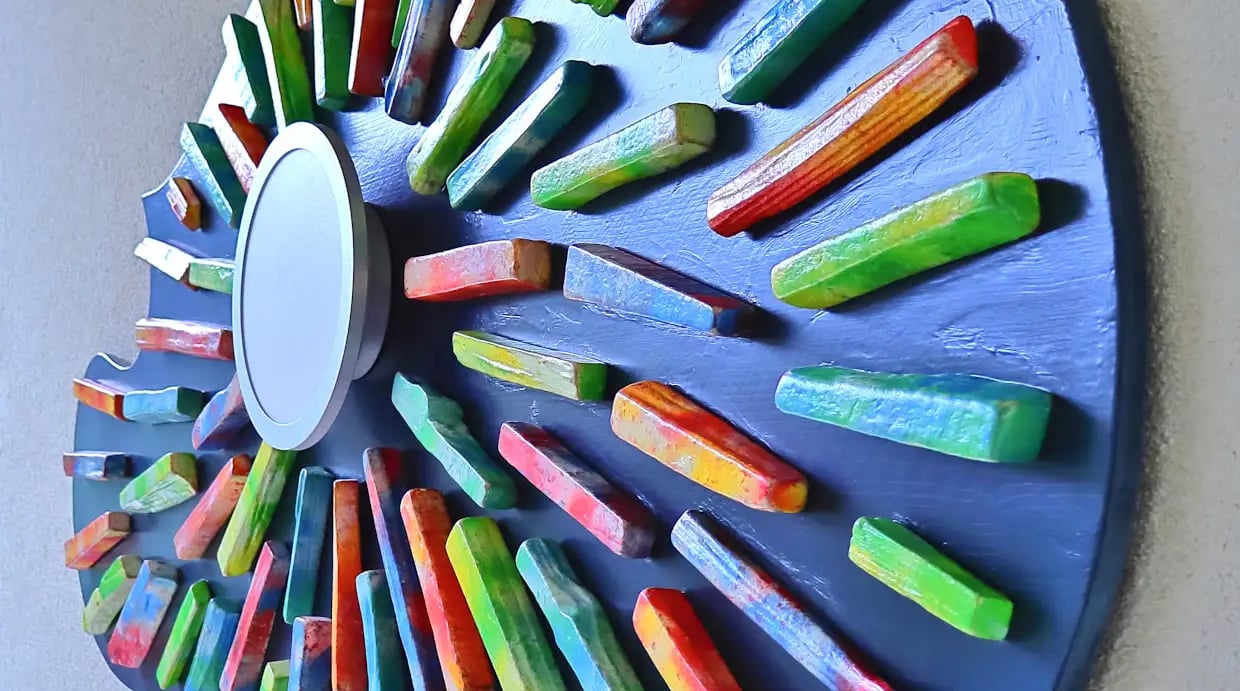 Nahaufnahme des real gewordenen Wandbildes aus sternförmig verklebten, bunten Holzscheiten mit integrierter Wandleuchte