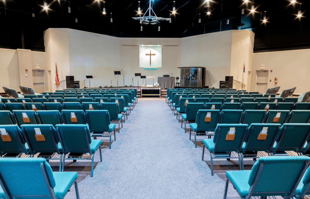 Intérieur de l'église avec des chaises, une estrades avec des micros 