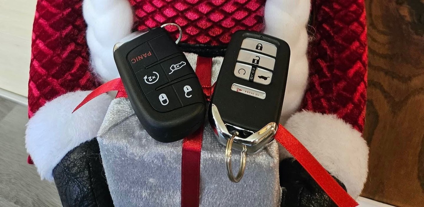 Two Honda key fobs placed on a Christmas-themed background