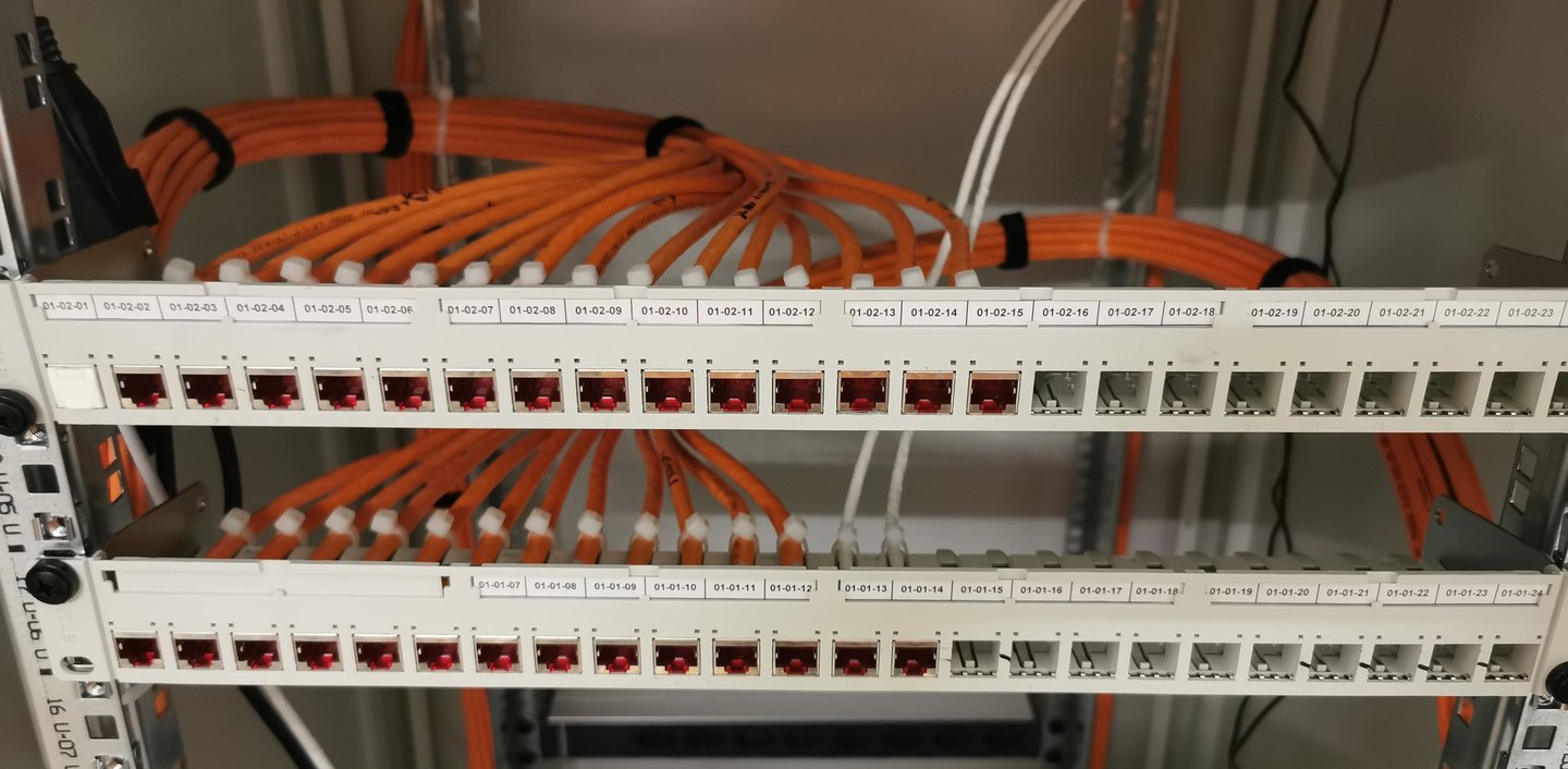 Labeled fiber optic patch panels with organized orange ethernet cables in a server rack.