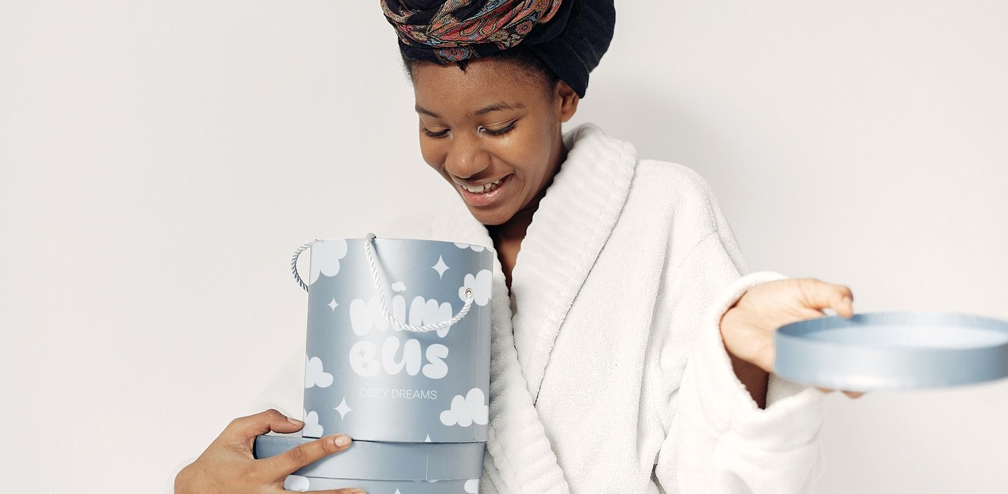 Fotografía de una mujer sujetando entre las manos una de las cajas del packaging de la marca Nimbus Cozy dreams