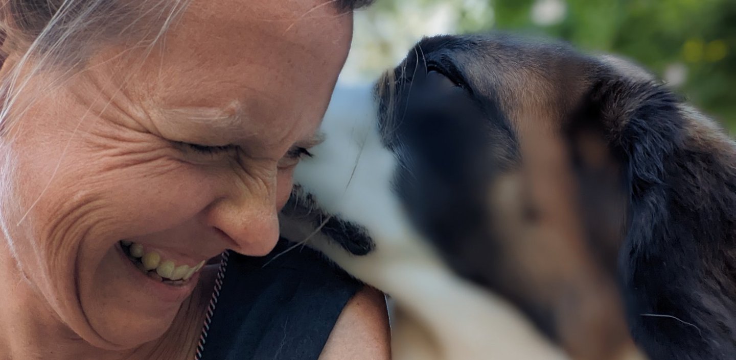a woman is smiling and holding a dog