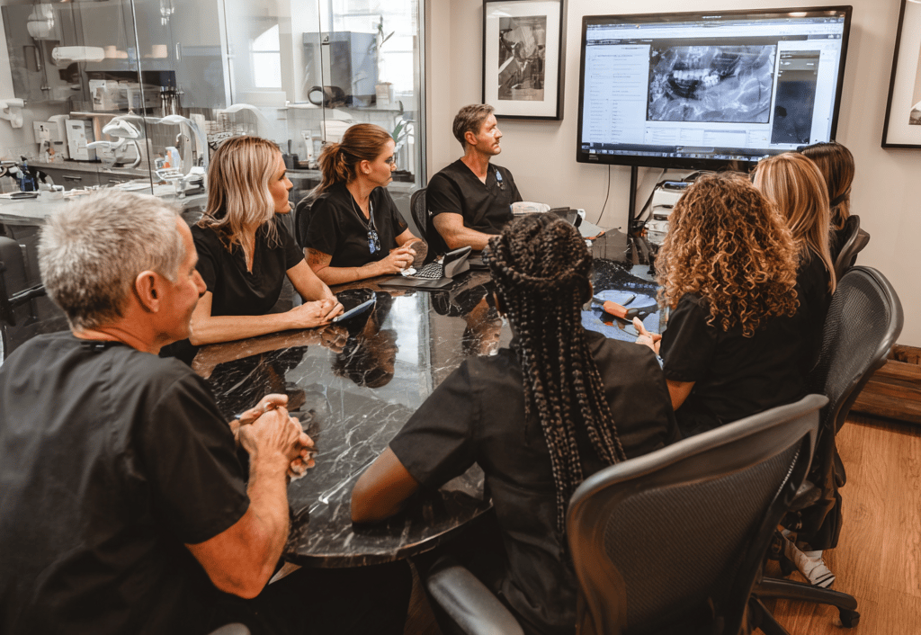 A professional dental team in a morning huddle meeting.