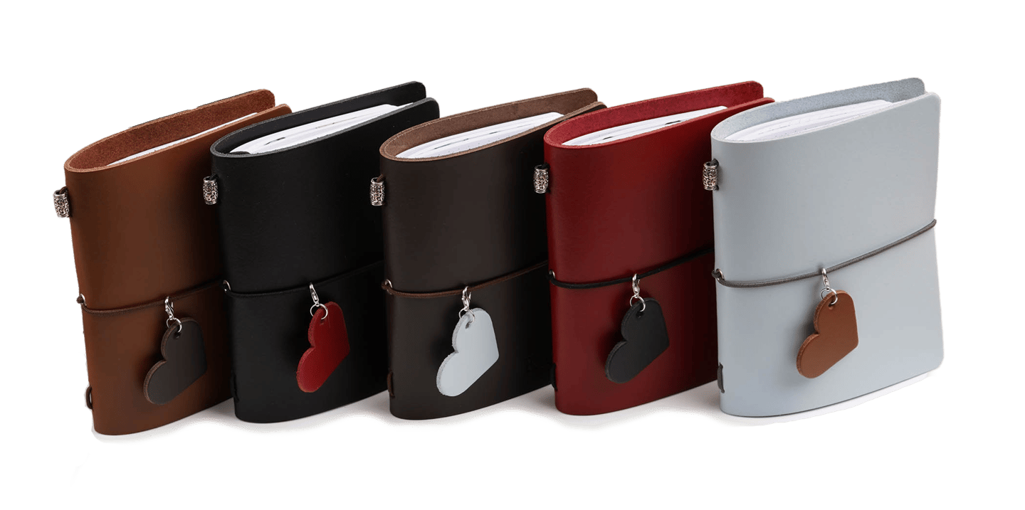 a group of four leather bound journals with a heart shaped leather tags