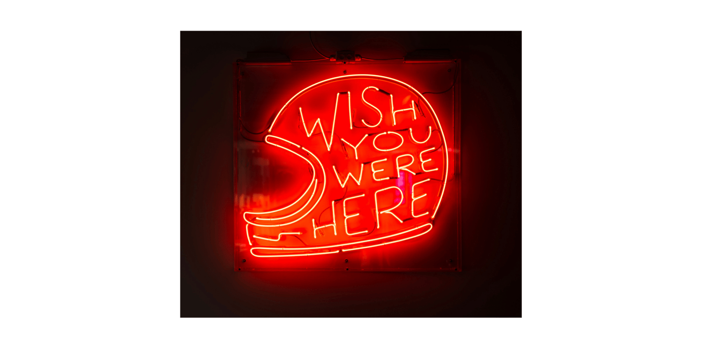 Neon Sign of motorcycle helmet saying Wish You Were Here to represent Motorcycle Riding