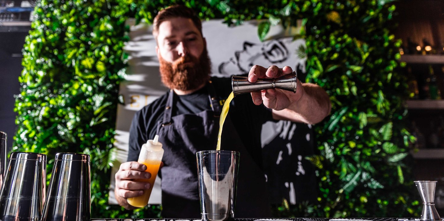 A bartender preparing a cocktail with various drinks 