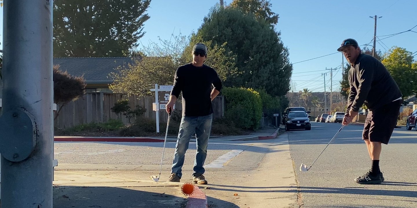 Street golf chip shot: two men aim for the urban capture hole