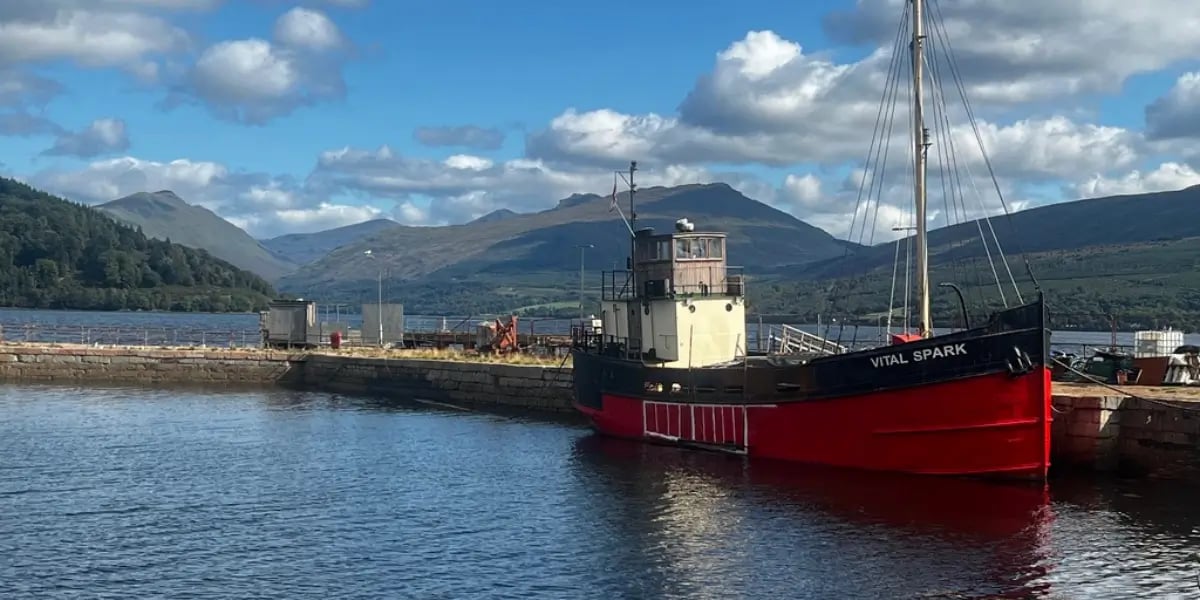a boat docked at a pier with hills in the background