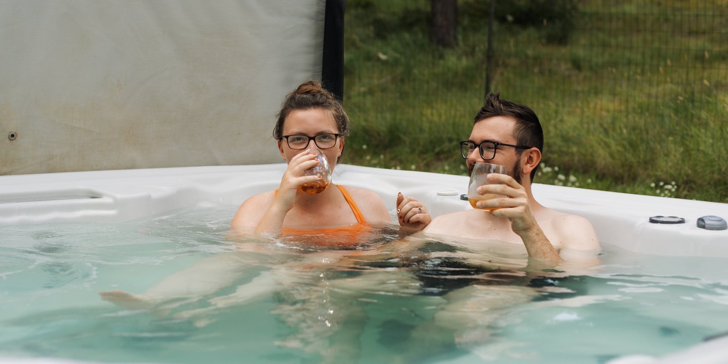 a man and woman in a hot tub drinking whiskey
