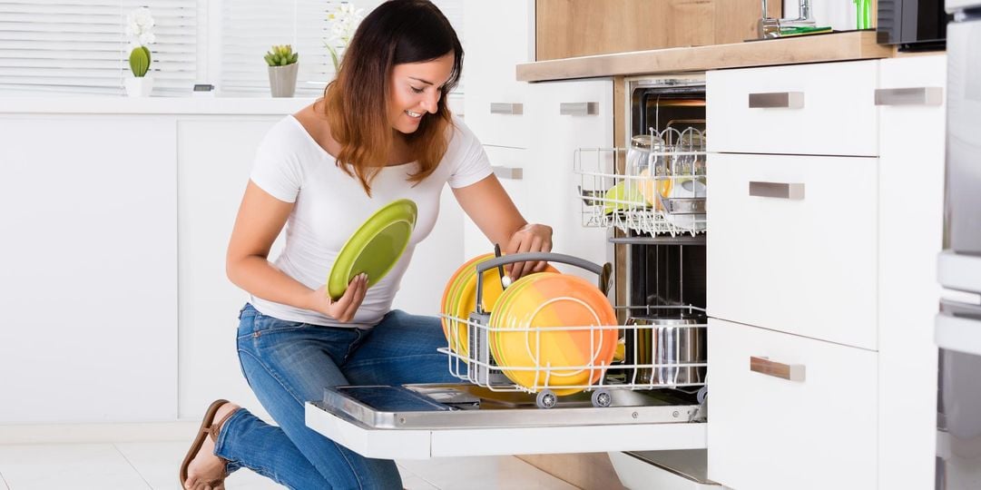 a women putting plates into a dishwasher